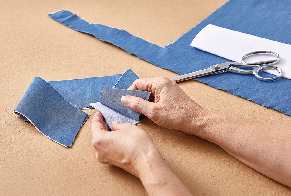 hands holding blue, cut fabric.