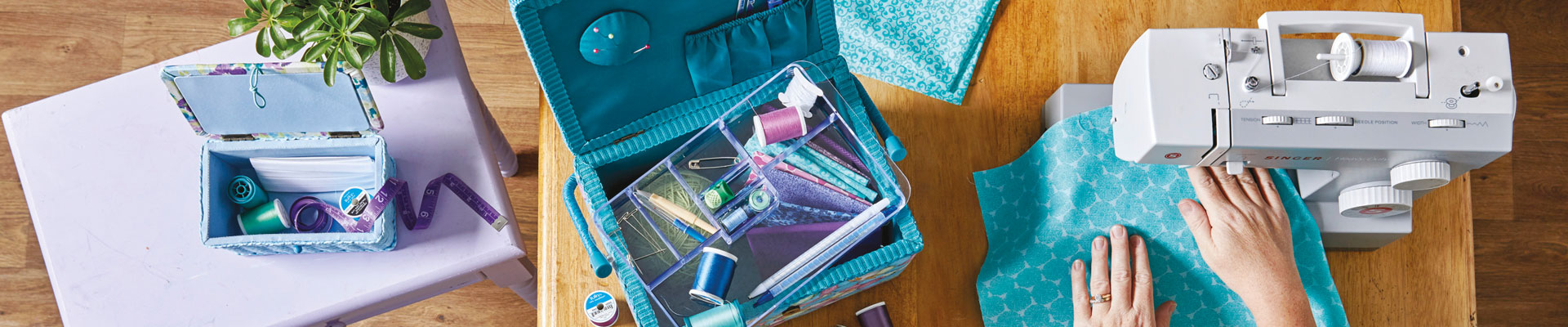 hands sewing blue fabric with a sewing machine surrounded by other dewing supplies