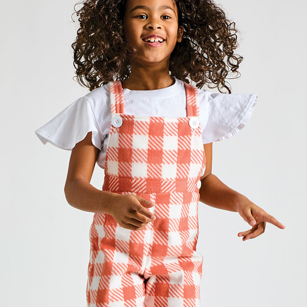 young girl in red and white checkered dress jumping