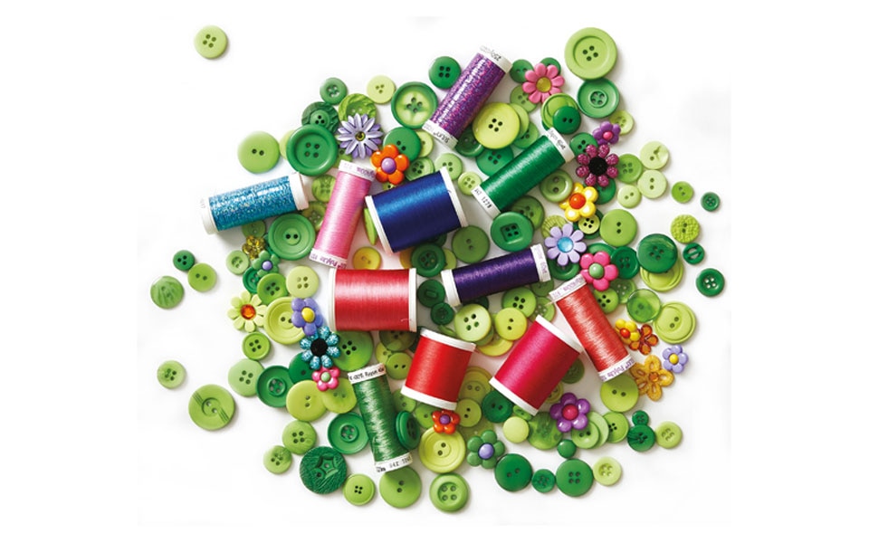 different sizes of threads on top of a pile of green buttons