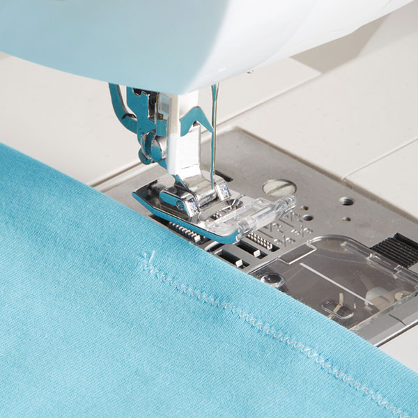 sewing machine sewing blue fabric with a zigzag stitch