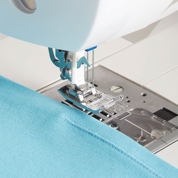 sewing machine sewing blue fabric with a double stitch