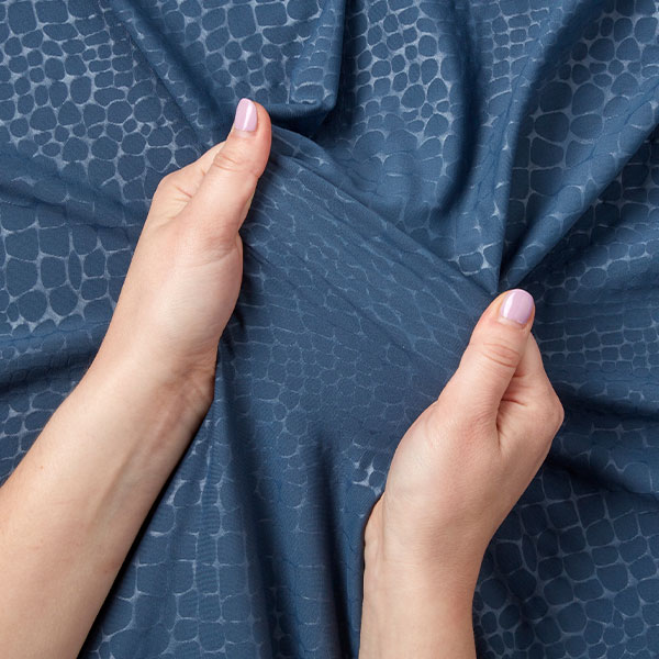 hands stretching out a long piece of blue performance fabric