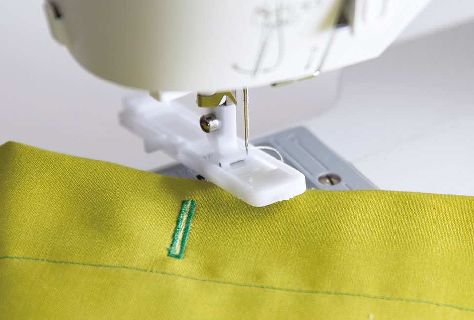 sewing machine sewing together green fabric
