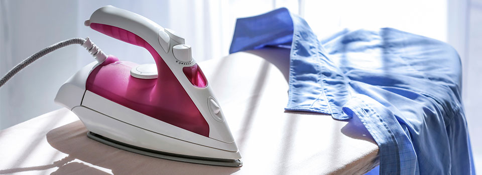 pink and white iron on an ironing board with a blue shirt